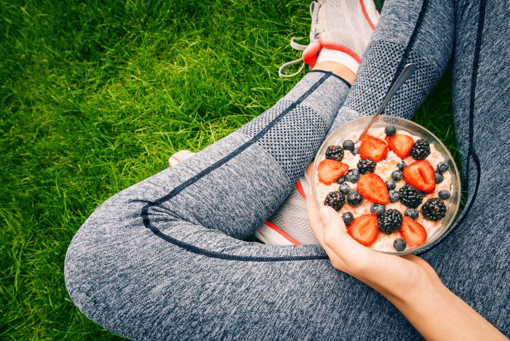 Young girl eating a oatmeal with berries after a workout . Fitness